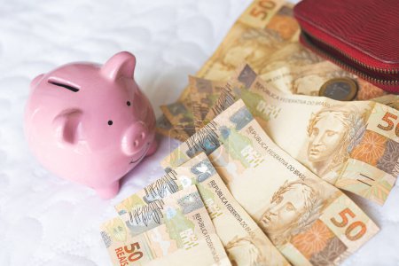 Photo for Brazilian money and piggy bank on a table. Brazilian economy and finance concept - Royalty Free Image