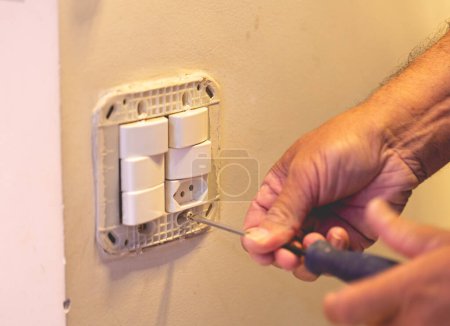 Foto de El hombre conecta un interruptor de luz eléctrica a la pared - Imagen libre de derechos