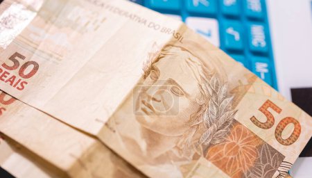 Téléchargez les photos : Real brésilien notes sur une calculatrice. Economie, finances et impôts brésiliens. - en image libre de droit