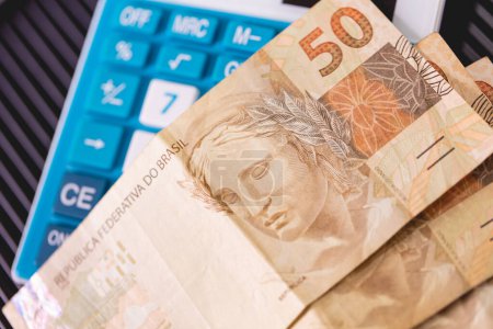 Téléchargez les photos : Real brésilien notes sur une calculatrice. Economie, finances et impôts brésiliens. - en image libre de droit