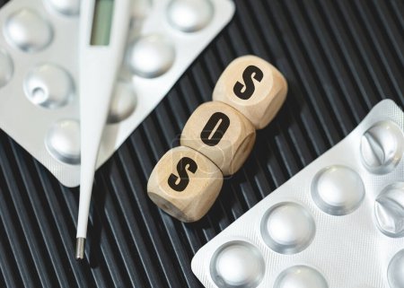 Photo for Inscription sos on wooden cubes with pills and thermometer - Royalty Free Image