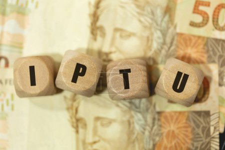 Photo for The initials IPTU written on wooden dice with Brazilian banknotes in the composition - Royalty Free Image
