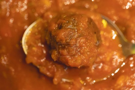 Photo for Close up view of delicious meatball with tomato sauce in spoon - Royalty Free Image