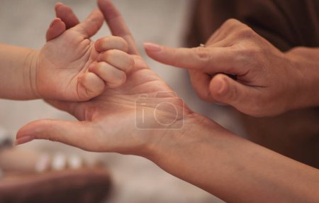 Téléchargez les photos : Mère tenant la main de son enfant. Parent jouer avec les mains de la petite fille, donnant une aide psychologique. Différentes générations sincères partageant des secrets de famille ou faisant la paix. - en image libre de droit