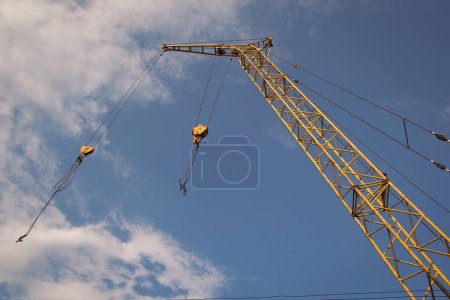 fragment of mobile crane boom against blue sky. Crane boom and structure take from below of crane at ground level. Industrial truck crane.
