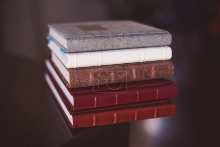A pile of books. multi-colored albums of different sizes and textures on a dark background.