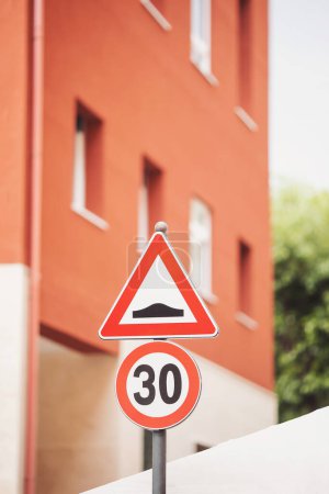 speed bump (aka as speed hump or sleeping policeman) to limit speed of cars traffic sign. 30 kph and speed bump road traffic signs in italian city, europe. Road sign.