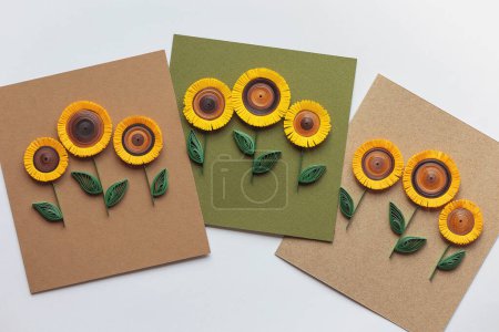 Quilling-Karte mit Sonnenblumen auf braunem Papier Hintergrund. Sommerblumen. Handgefertigt aus Grußkarten in Papierquilttechnik. Handwerk zu Hause. Hobby, home office.