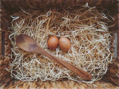 Organic fresh eggs and  wooden spoon in a straw nest. Easter eggs on wooden straw background in the early morning on Easter Holiday. Cooking concept. ready to cook. the concept of making dough. 