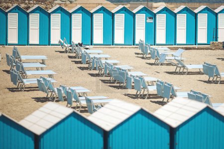 Strand mit seinen Holzhütten und Sonnenschirmen oder Sonnenschirmen an einem öffentlichen Strand. Strandhütten am berühmten Strand von Portofino, in der Nebensaison. Portofino, Italien, Europa.