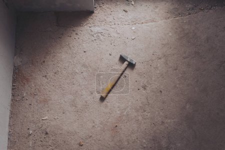 Stahlhammer auf Betonboden. Starker Hammer mit Holzstiel. Weinlese des Hammers auf Zementboden für Hintergrund.