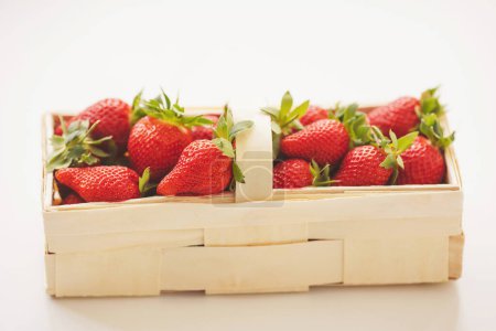 Fresas en una cesta de madera y sobre un fondo blanco. Fresas frescas jugosas. 