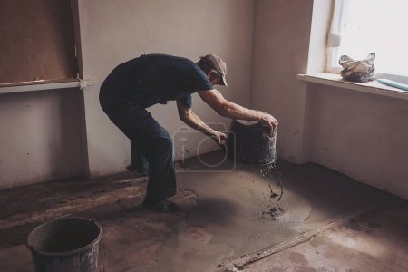 Arbeiter gießen Beton auf den Boden. Wohnung während Renovierung.