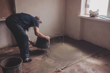 Worker pouring concrete on the floor.  apartment during renovation.