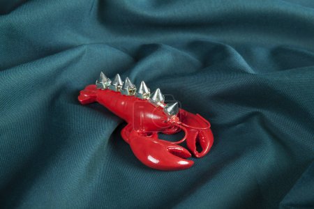 Photo for A punk style lobster wearing riveted spikes like a mohican on a green wavy fabric background. Minimal color still life photography. - Royalty Free Image