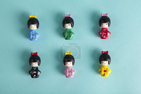 Téléchargez les photos : Une collection de 6 poupées kokeshi en bois alignées en rangées et en colonnes sur un fond turquoise. Photographie de nature morte minimaliste et tendance. - en image libre de droit