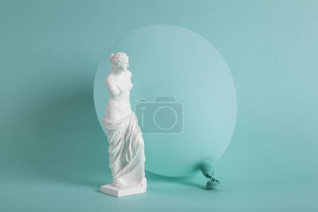 Photo for A Venus de Milo in front of a turquoise balloon in the same color as the background. Monochrome and shades of color. Contrast between a classic sculpture and a vibrant contemporary turquoise background. - Royalty Free Image