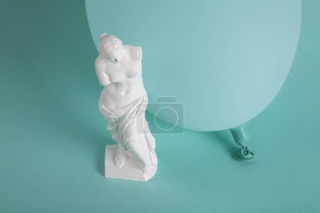 Téléchargez les photos : Une Vénus de Milo devant un ballon turquoise de la même couleur que le fond. Monochrome et nuances de couleur. Contraste entre une sculpture classique et un fond turquoise contemporain vibrant. - en image libre de droit
