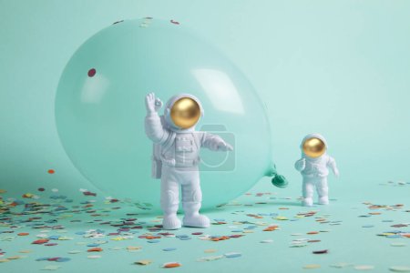Téléchargez les photos : Un couple de cosmonautes explorant une nouvelle planète. Ils sont entourés de confettis et de ballons. Le tout est monochrome turquoise. Photographie de nature morte minimaliste et tendance. - en image libre de droit