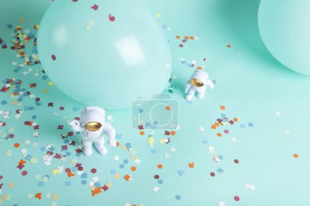 Foto de Una pareja cosmonauta explorando un nuevo planeta. Están rodeados de confeti y globos. El todo es turquesa monocromo. Minimalista, fotografía bodegón de moda. - Imagen libre de derechos