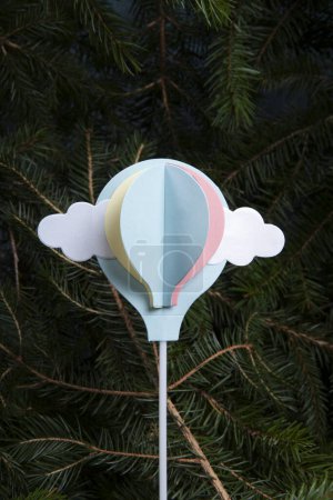 Foto de Un globo aerostático de papel, inicialmente una decoración de pasteles, volando desde un bosque de abetos. Una ilustración poética de la libertad - Imagen libre de derechos