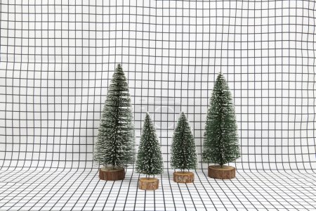 Photo for A miniature forest scene composed of several small christmas trees on a graphic black and white grid background. minimal still life photography - Royalty Free Image
