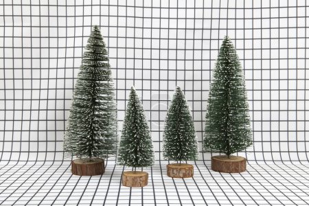 Photo for A miniature forest scene composed of several small christmas trees on a graphic black and white grid background. minimal still life photography - Royalty Free Image