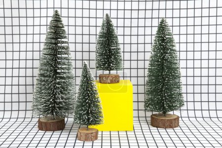 Photo for A miniature forest scene composed of several small christmas trees and a yellow cube on a graphic black and white grid background. minimal still life photography - Royalty Free Image