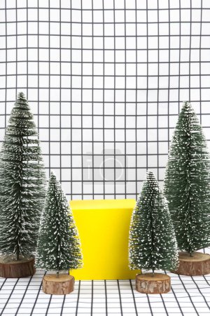 Foto de Una escena de bosque en miniatura compuesta por varios pequeños árboles de navidad y un cubo amarillo sobre un fondo gráfico de rejilla en blanco y negro. fotografía de naturaleza muerta mínima - Imagen libre de derechos