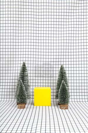 Téléchargez les photos : Une scène de forêt miniature composée de plusieurs petits arbres de Noël et d'un cube jaune sur fond de grille graphique noir et blanc. photographie de nature morte minimale - en image libre de droit