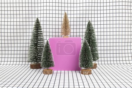 Téléchargez les photos : Une scène de forêt miniature composée de plusieurs petits arbres de Noël et d'un cube rose sur fond de grille graphique noir et blanc. photographie de nature morte minimale - en image libre de droit