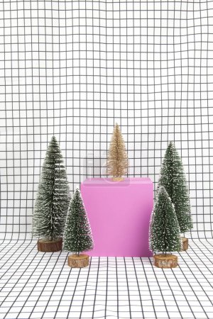 Foto de Una escena de bosque en miniatura compuesta por varios pequeños árboles de navidad y un cubo rosa sobre un fondo gráfico de rejilla en blanco y negro. fotografía de naturaleza muerta mínima - Imagen libre de derechos