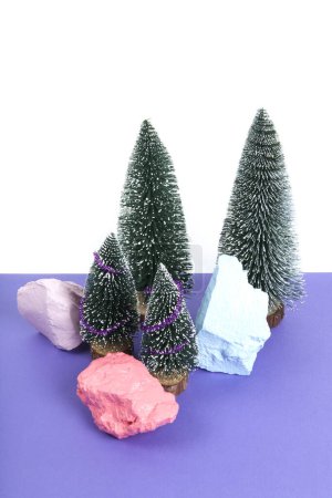 Photo for Miniature forest of christmas tree decorated with mini shiny garlands. Violet background. Minimal still life photography - Royalty Free Image