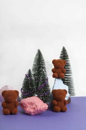 Photo for A band of teddy bears sitting on colorful rocks surrounded by snow-covered fir trees.White and Violet background. Minimal still life photography - Royalty Free Image