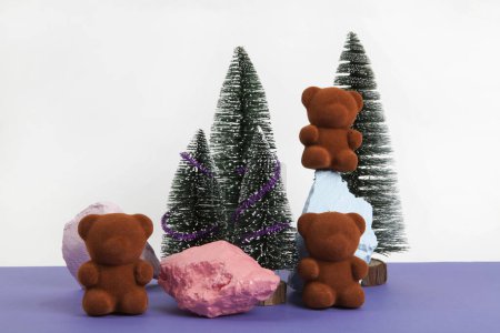Photo for A band of teddy bears sitting on colorful rocks surrounded by snow-covered fir trees.White and Violet background. Minimal still life photography - Royalty Free Image