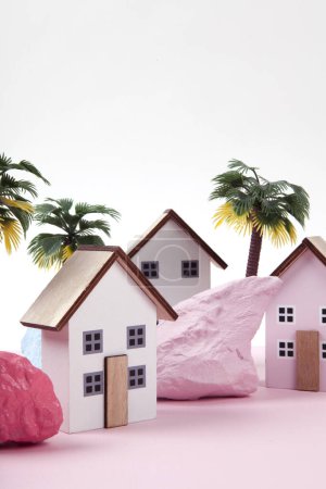 Photo for Model of miniature beach houses representing a vacation village in a harmony of pink surrounded by palm trees and rocks painted in different colors. Bright colors and minimal pop art photography - Royalty Free Image
