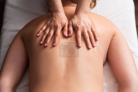 Téléchargez les photos : Masseur massant le dos et les omoplates de la jeune femme sur table de massage sur fond blanc. Concept de massages spa. procédures de relaxation du corps. Gros plan - en image libre de droit