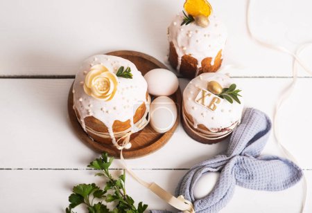 Téléchargez les photos : Gâteaux de Pâques au design délicat, léger et moderne et œufs sur fond de bois blanc avec jonquilles jaunes. Concept de Pâques. Cuisine traditionnelle de Pâques. Symbole de Pâques - en image libre de droit