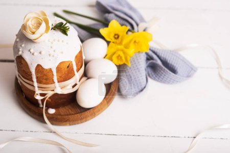 Téléchargez les photos : Gâteaux de Pâques au design délicat, léger et moderne et œufs sur fond de bois blanc avec jonquilles jaunes. Concept de Pâques. Cuisine traditionnelle de Pâques. Symbole de Pâques - en image libre de droit