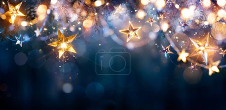 Foto de Luces de Navidad - Estrellas Cuerdas colgando en ramas de abeto en fondo desenfocado abstracto - Imagen libre de derechos
