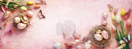 Photo for Easter Golden Eggs On Pink Background With Tulips And Nest - Royalty Free Image