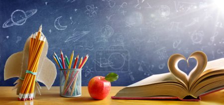 Téléchargez les photos : Retour à l'école - Livre avec fusée et crayons colorés sur le bureau avec tableau noir - Concept de démarrage - en image libre de droit