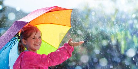 Téléchargez les photos : Enfant heureux avec parapluie sous la pluie Joie et rire avec douche d'automne - en image libre de droit