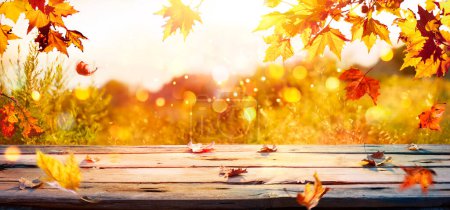 Téléchargez les photos : Automne - Feuilles branche sur la table en bois au coucher du soleil avec des lumières abstraites déconcentrées et effet scintillant - en image libre de droit