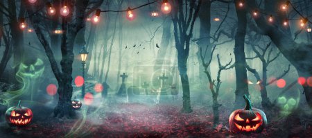 Téléchargez les photos : Halloween - Forêt chassée avec des citrouilles et des fantômes au clair de lune - Jack O Lanternes dans le cimetière avec de la lumière à cordes au crépuscule - en image libre de droit
