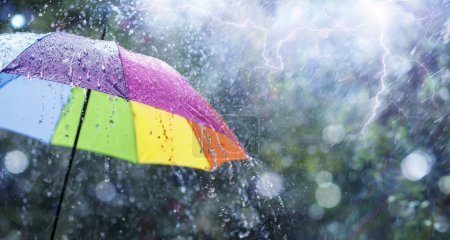 Foto de Lluvia en el paraguas del arco iris - Concepto del tiempo - Ducha de primavera y otoño con gotas desenfocadas abstractas y efectos de llamarada de luz - Imagen libre de derechos