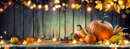 Téléchargez les photos : Thanksgiving - Citrouilles et Corncobs sur la table rustique avec guirlande et lumières abstraites déconcentrées - en image libre de droit