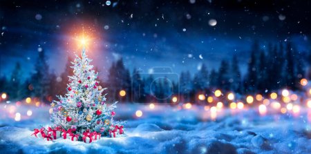 Téléchargez les photos : Arbre de Noël et boîtes-cadeaux sur la neige dans la nuit avec étoile brillante et forêt - Paysage abstrait d'hiver - en image libre de droit