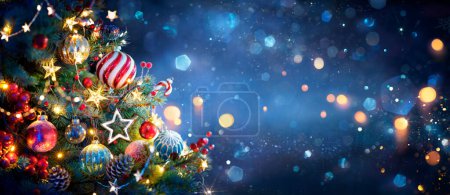 Téléchargez les photos : Arbre de Noël avec des ornements dans les lumières bleues et bokeh - Véritables branches de sapin avec scintillement en arrière-plan abstrait déconcentré - Cette image contient des éléments de rendu 3d - en image libre de droit