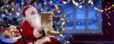 Téléchargez les photos : Père Noël dans sa maison lisant la liste de souhaits la nuit - Arbre de Noël et fenêtre avec des lumières déconcentrées abstraites Bokeh - en image libre de droit